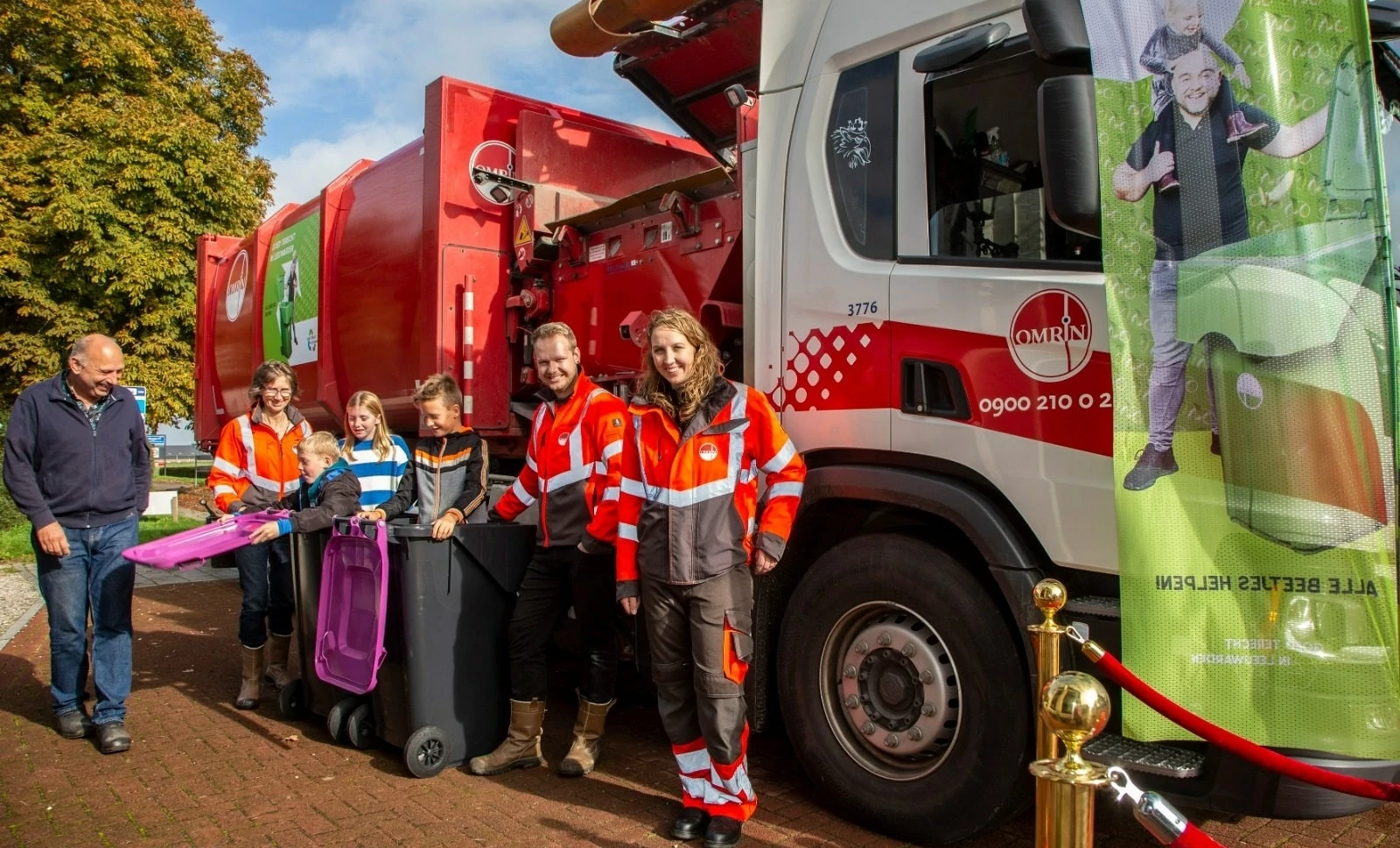 Afvalwagen met personen ervoor
