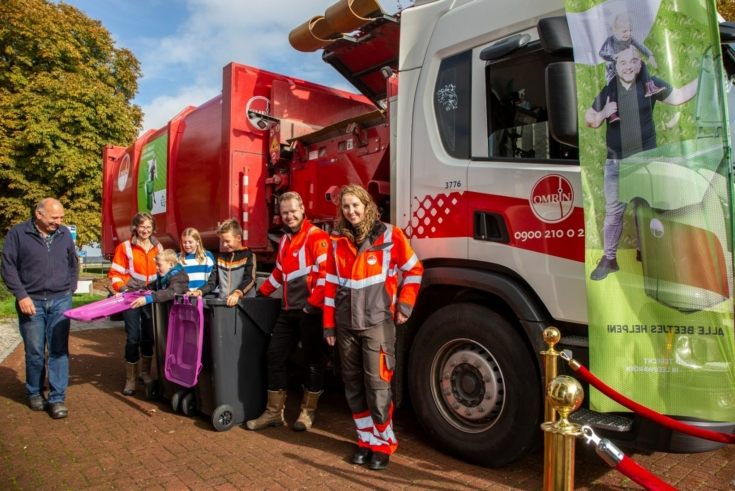 Afvalwagen met personen ervoor