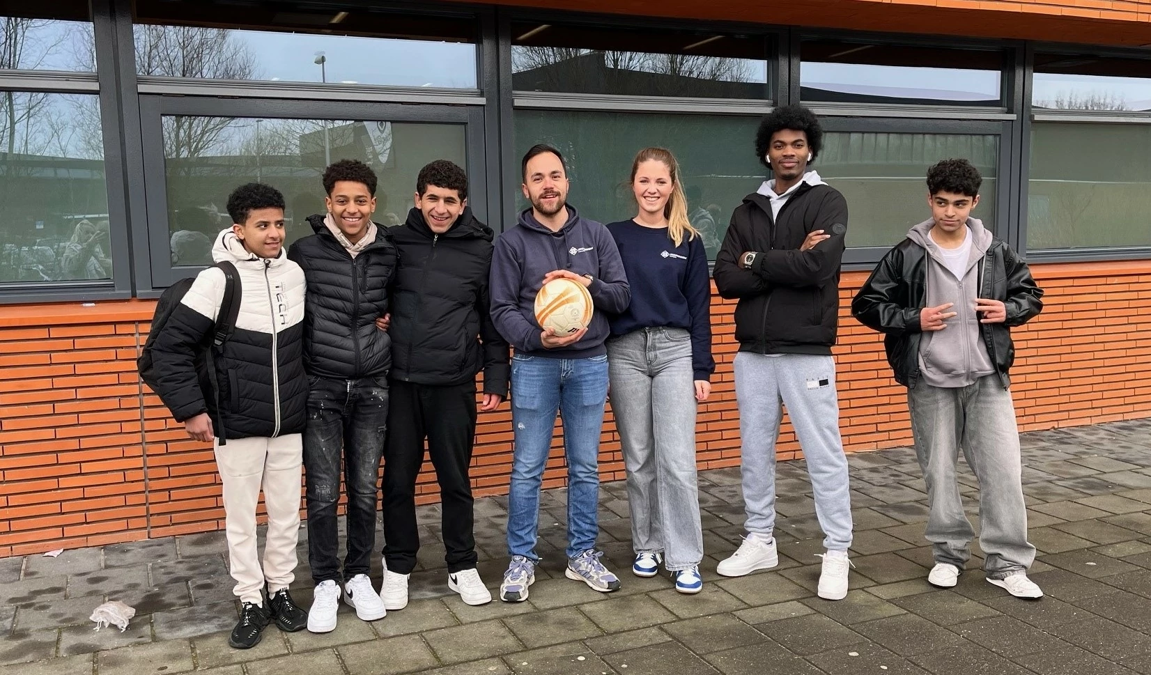 Jongeren en leerkracht voor hun school